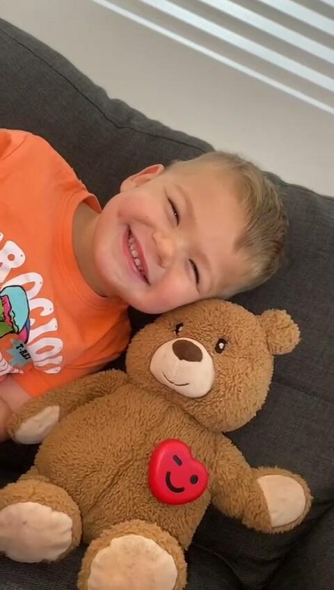 A smiling child beside a teddy fitted with the red ToyPal One heart